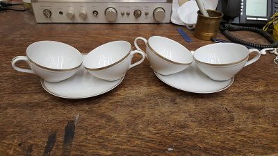 White tea cups and saucers with golden accents